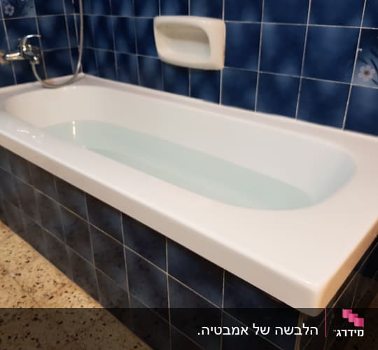 אמבטיה עם חיפוי אריחים כחולים וברז מתכת